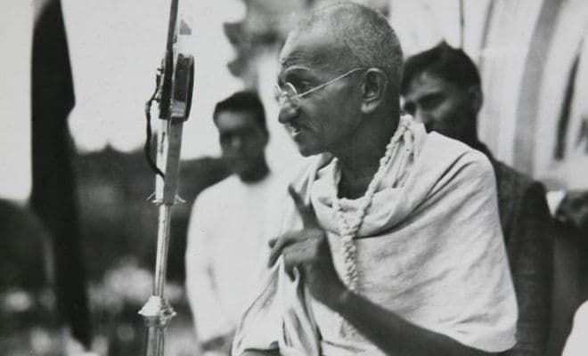 Mahatma Gandhi speaking into a microphone